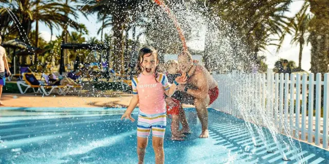 Family having fun in the splash zone at TUI BLUE Playa Feliz in Gran Canaria.